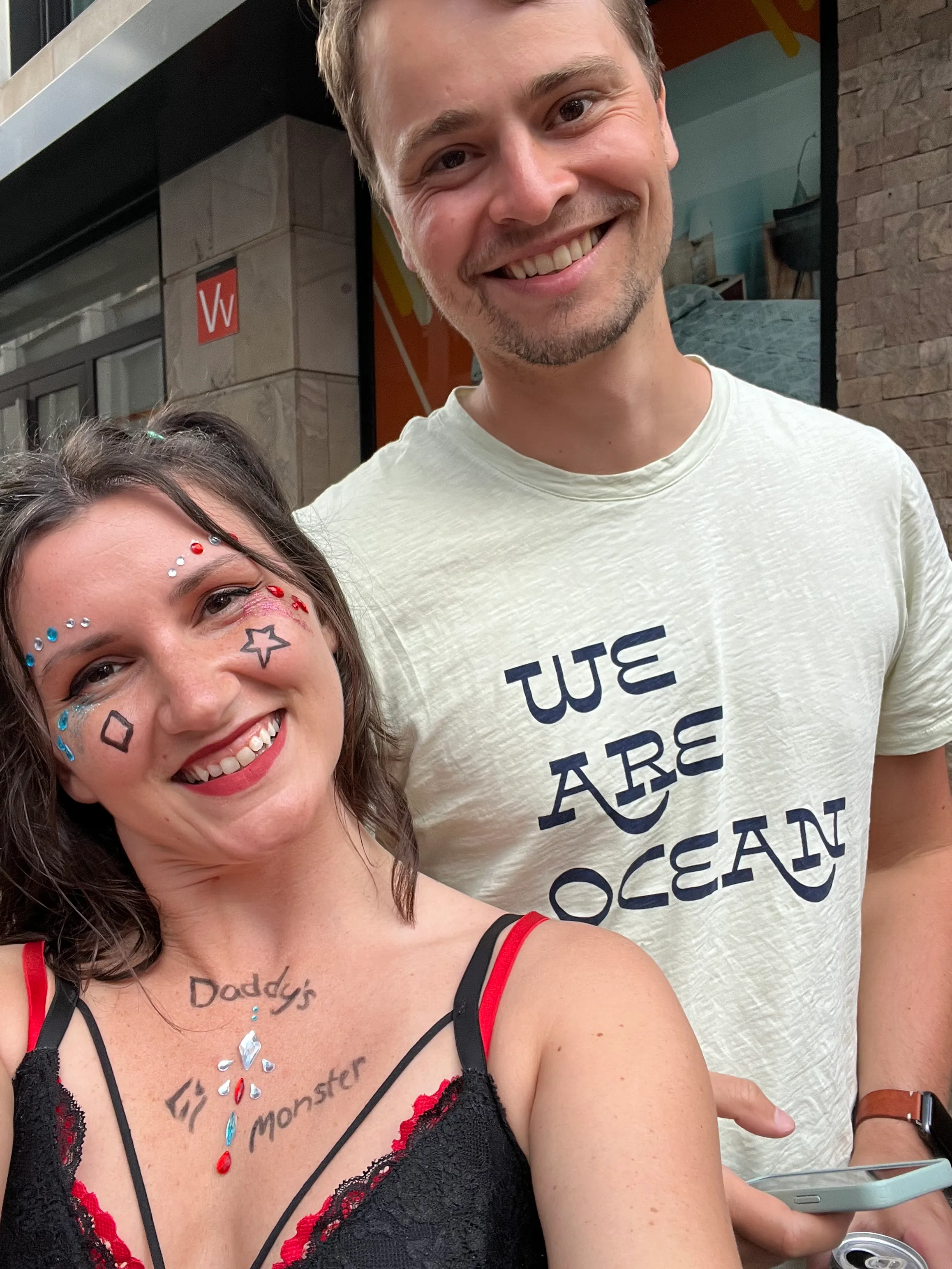 Selfie of Jillian and Connor. Jillian is dressed up as Harlie Quinn with facepaint, colorful gemstones and glitter. Connor is slightly sunburned.